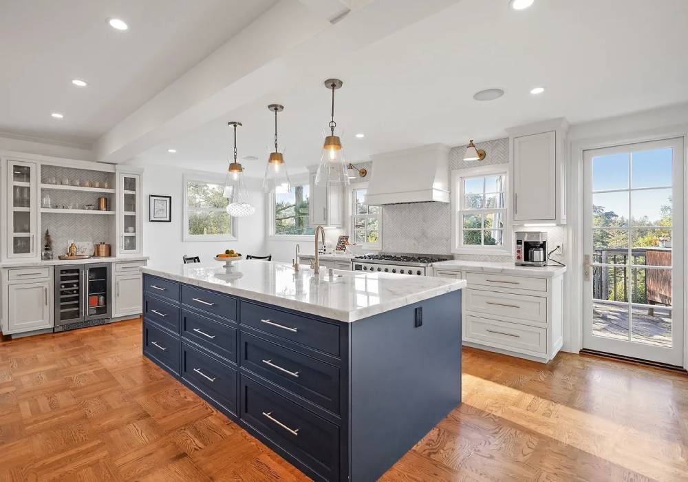 A kitchen with white cabinets and wood floors.