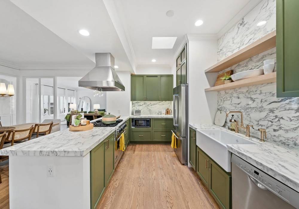 A kitchen with green cabinets and white counters.