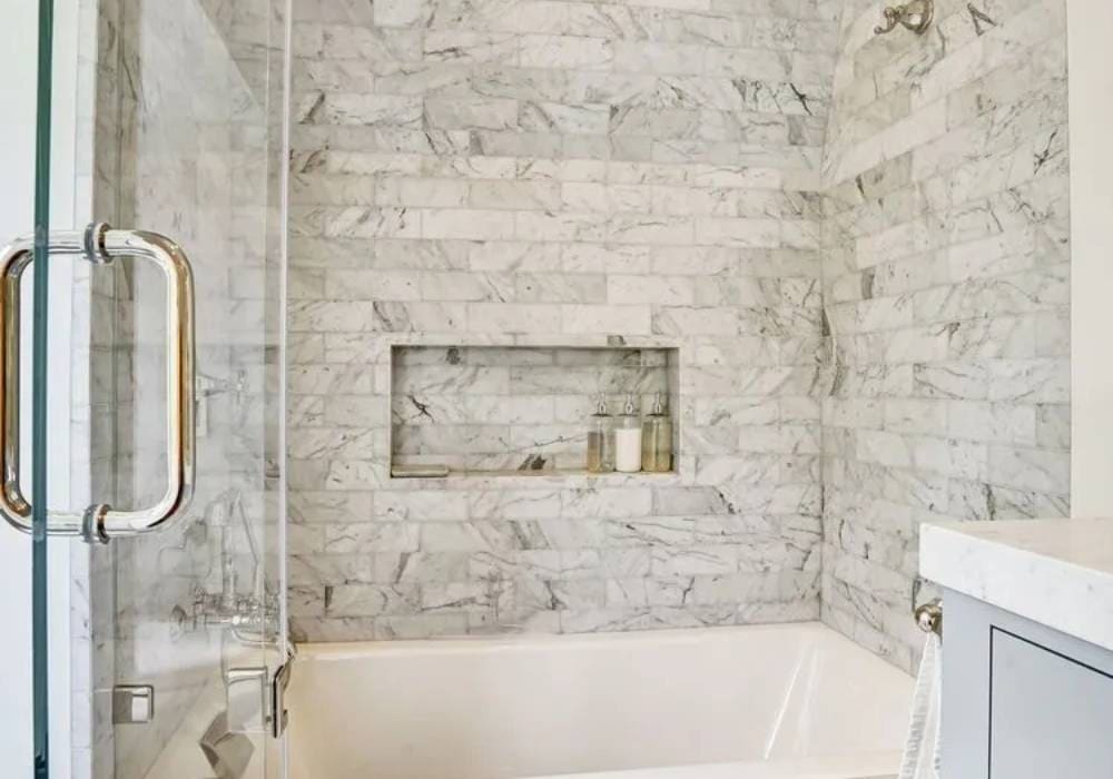 A bathroom with a tub and shower, tiled walls.