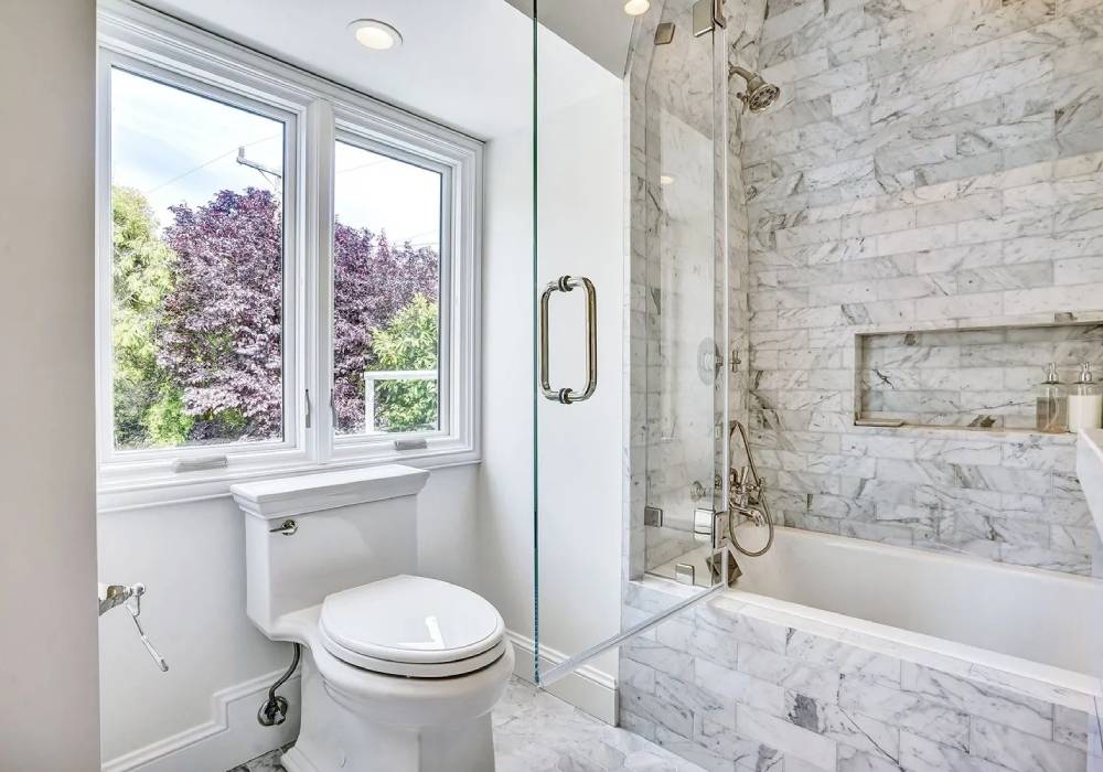 A bathroom with marble walls and floors, toilet and tub.