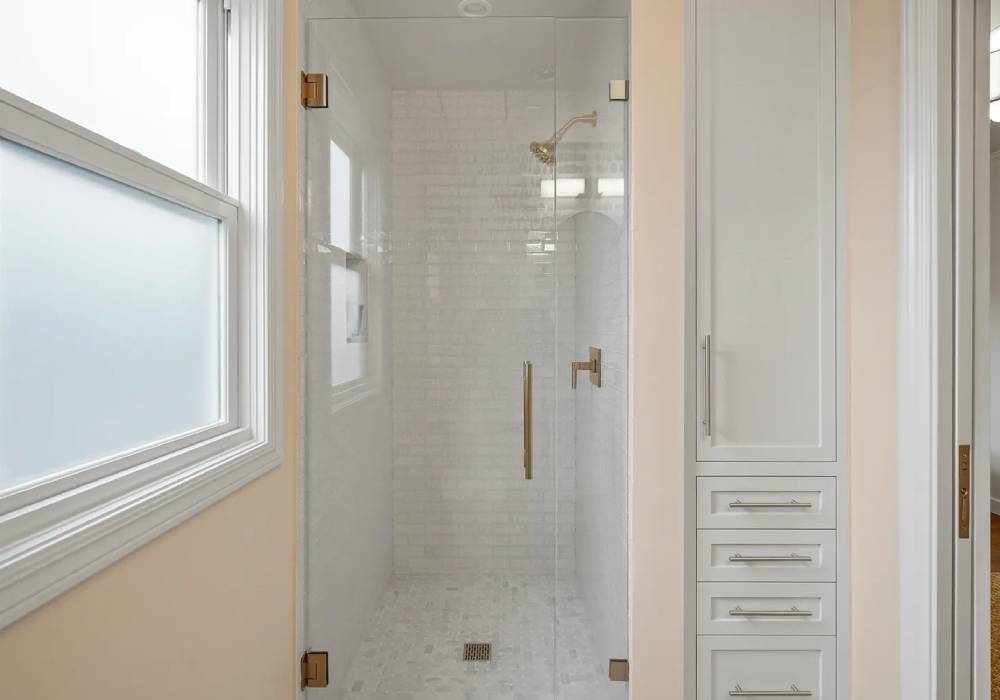 A bathroom with a walk in shower and window.