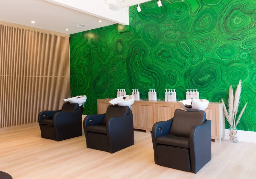 A room with three black chairs and green walls