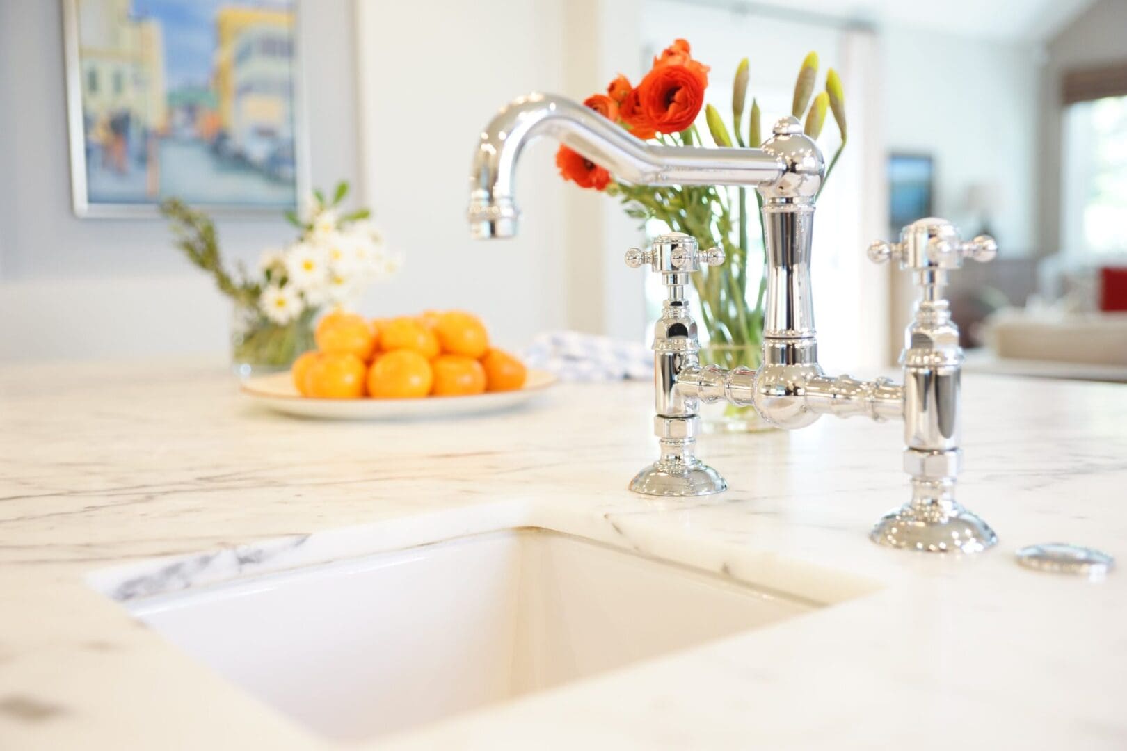 A white sink with flowers and fruit on the counter.