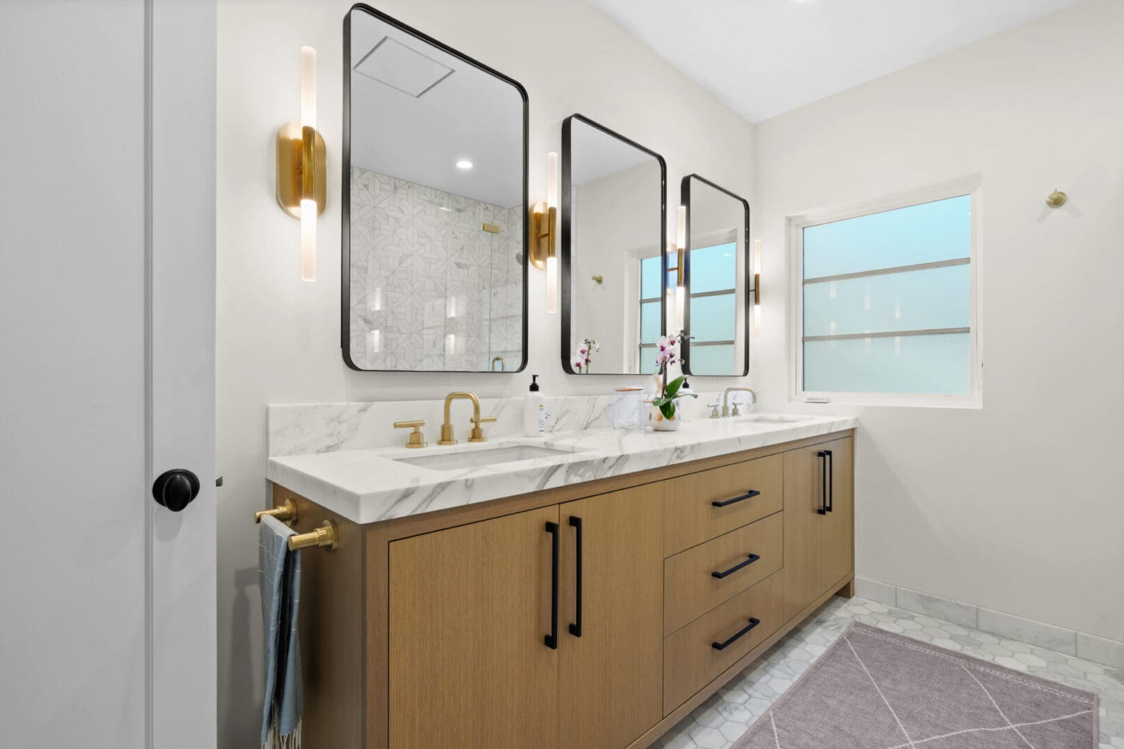 A bathroom with three mirrors and two sinks.