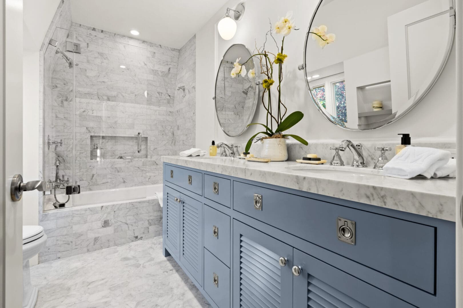 A bathroom with blue cabinets and marble tile.