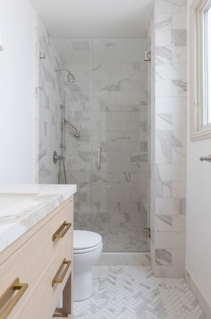 A bathroom with marble tile and white walls.