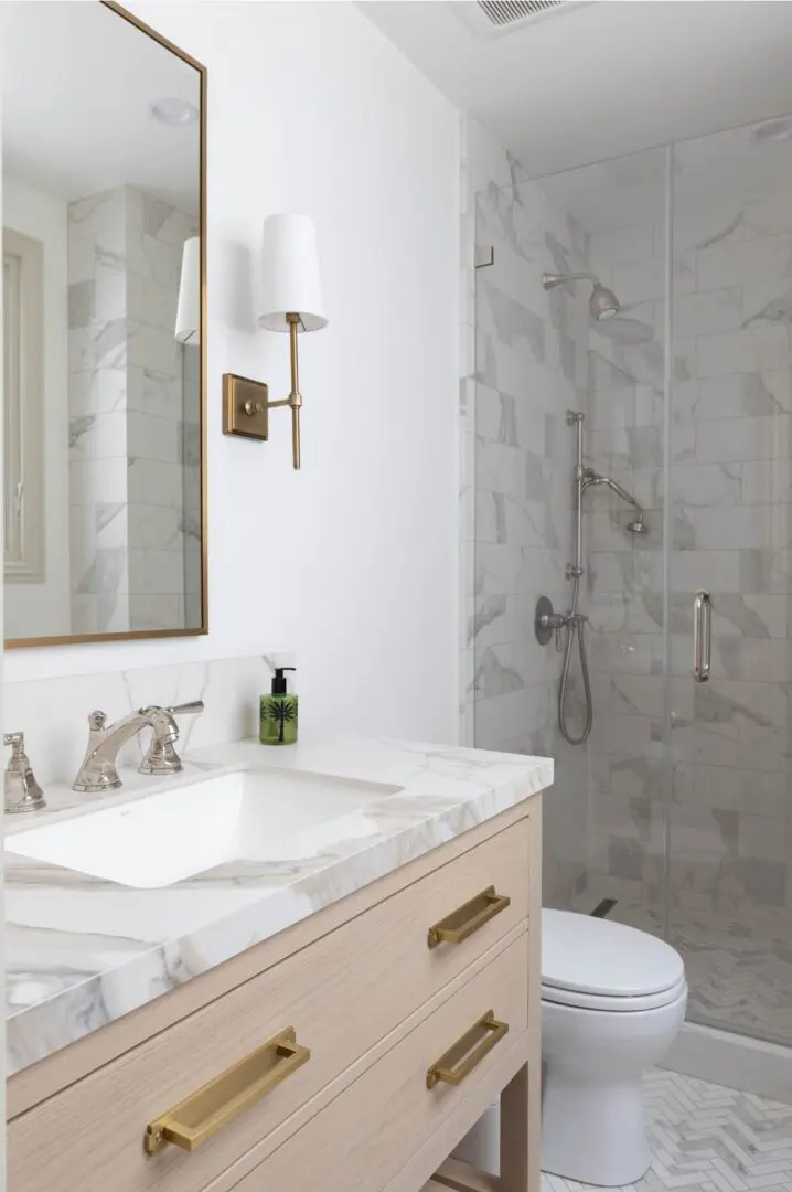 A bathroom with marble walls and floors, white vanity and toilet.