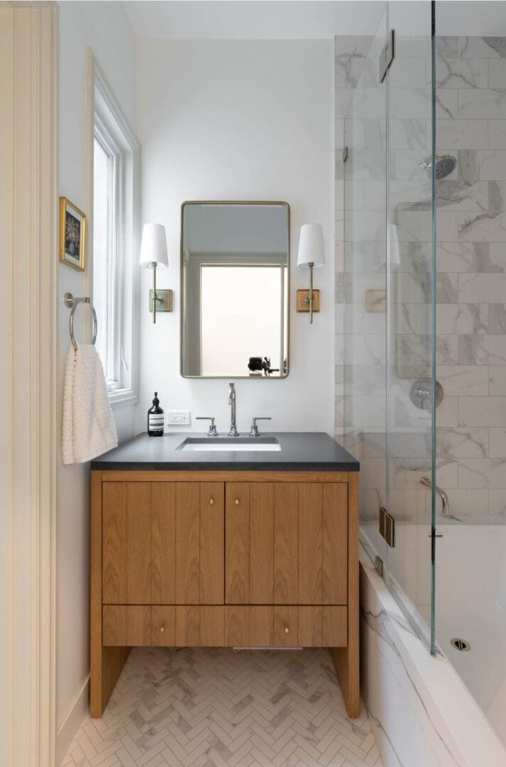 A bathroom with a sink, mirror and shower.