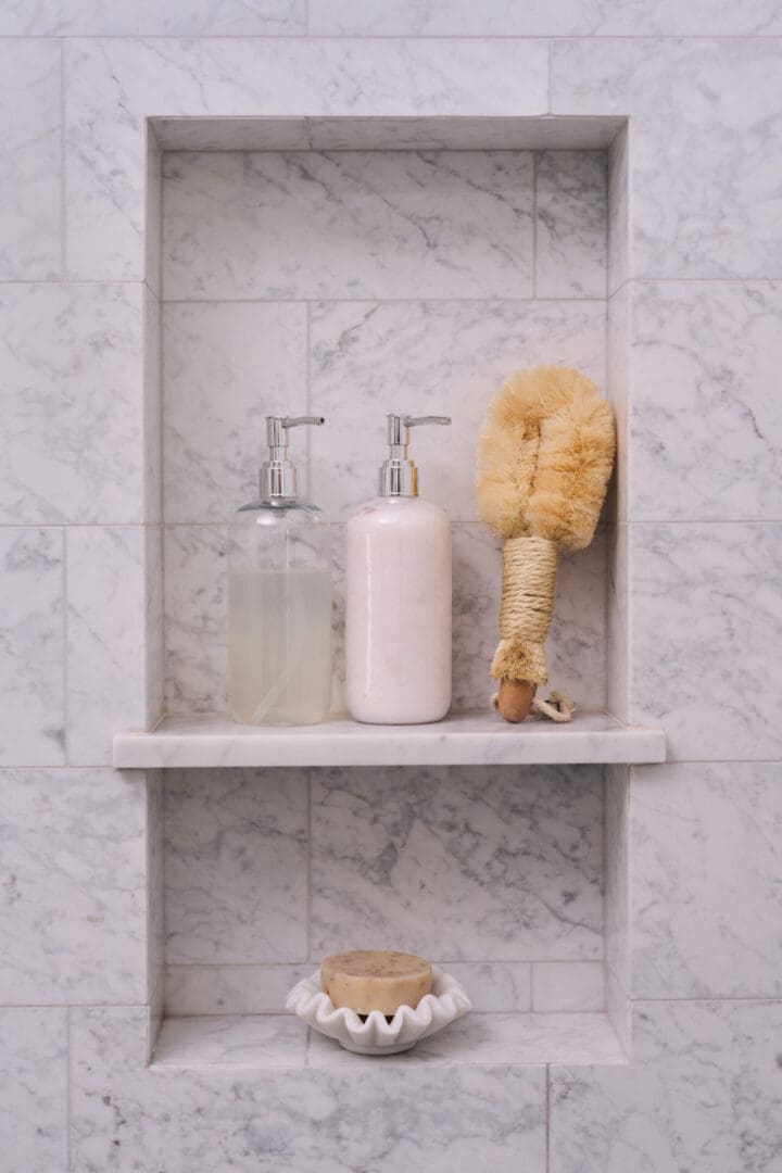 A bathroom shelf with soap and brushes on it.