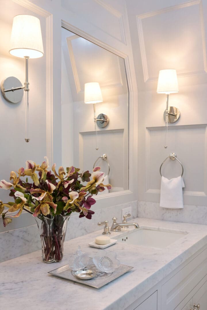 A bathroom with white walls and a vase of flowers.