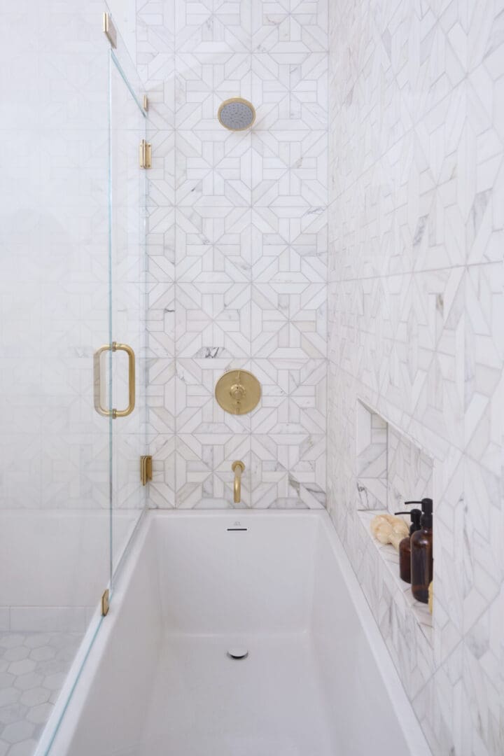 A bathroom with marble walls and gold fixtures.