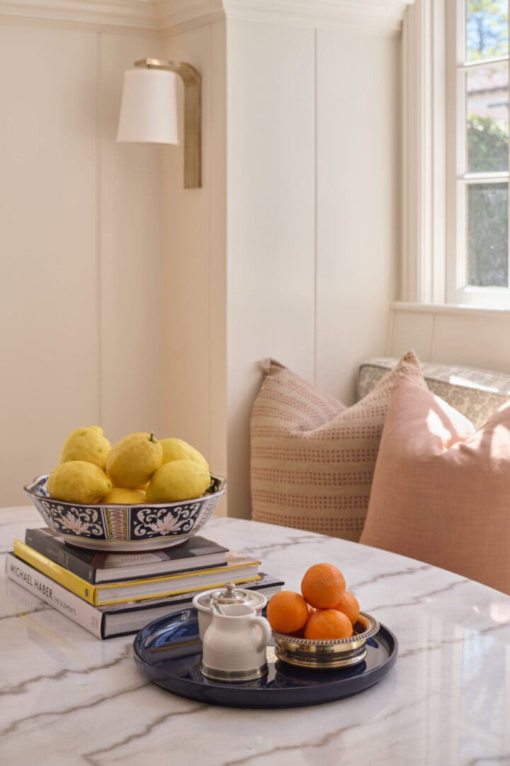 A bowl of lemons and oranges on top of a table.