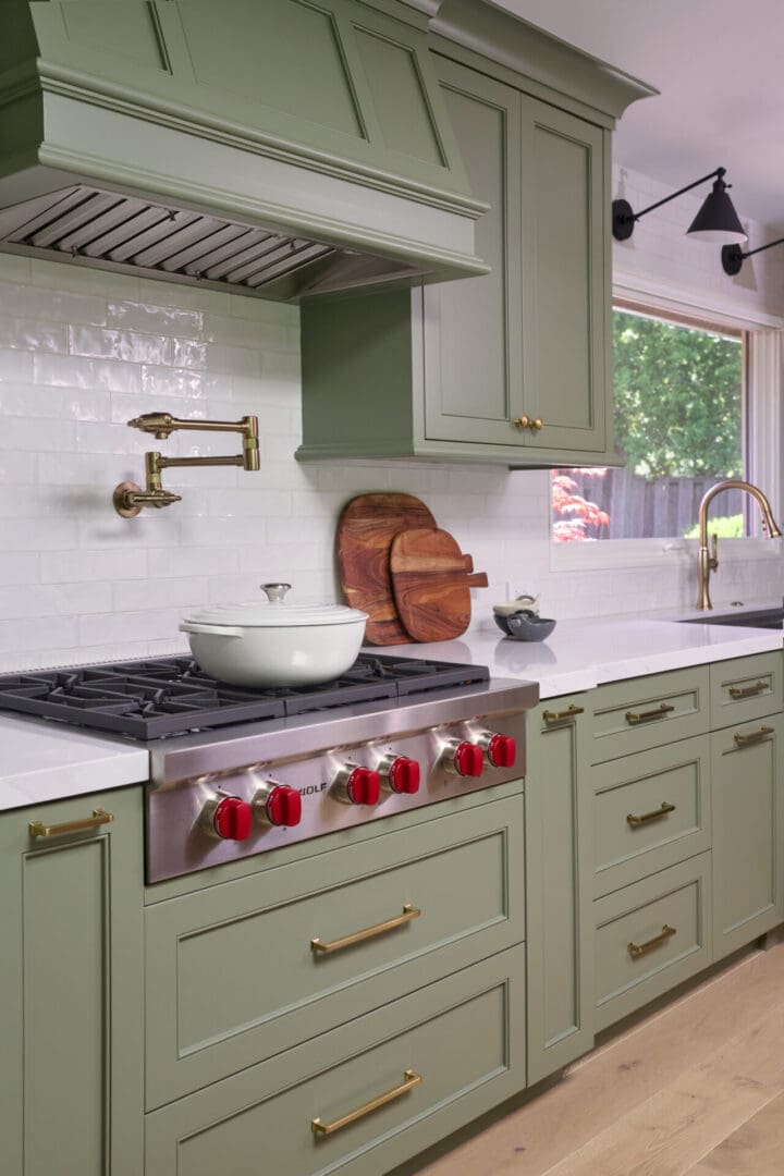 A kitchen with green cabinets and white counters.