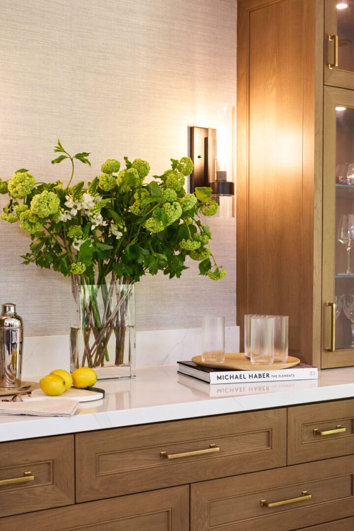 A kitchen counter with a vase of flowers and lemons.