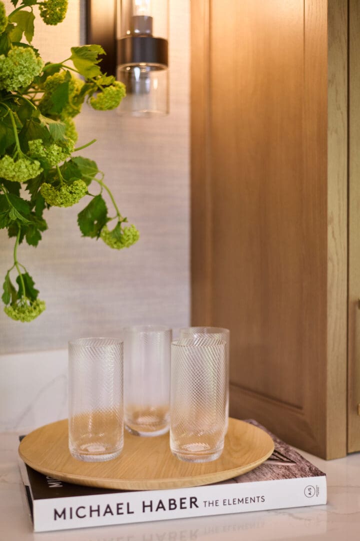 A table with four glasses and a plant hanging from the ceiling.