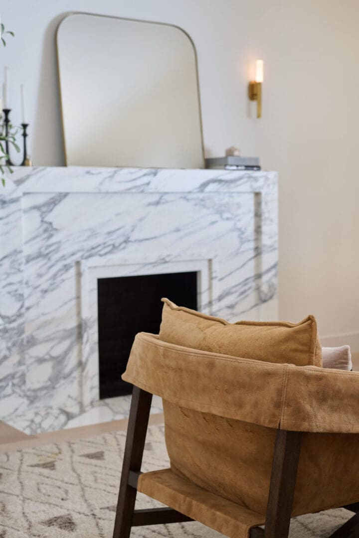 A fireplace with a marble mantle and white walls.