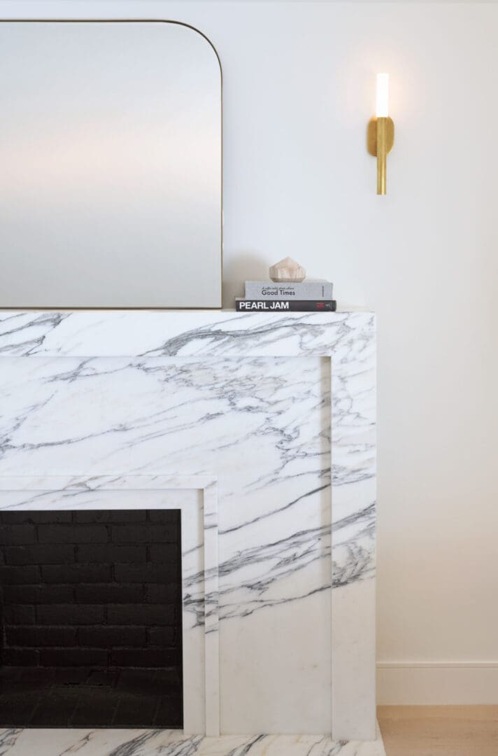 A marble fireplace with a gold mirror above it.