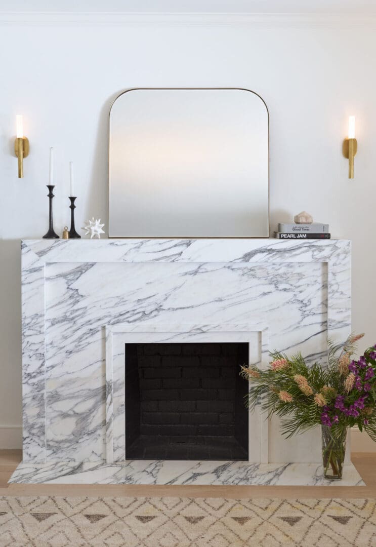 A marble fireplace with a mirror above it.