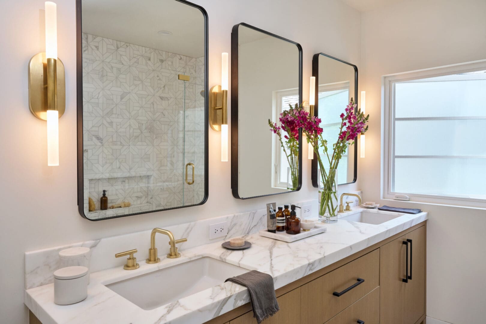 A bathroom with three mirrors and two sinks.