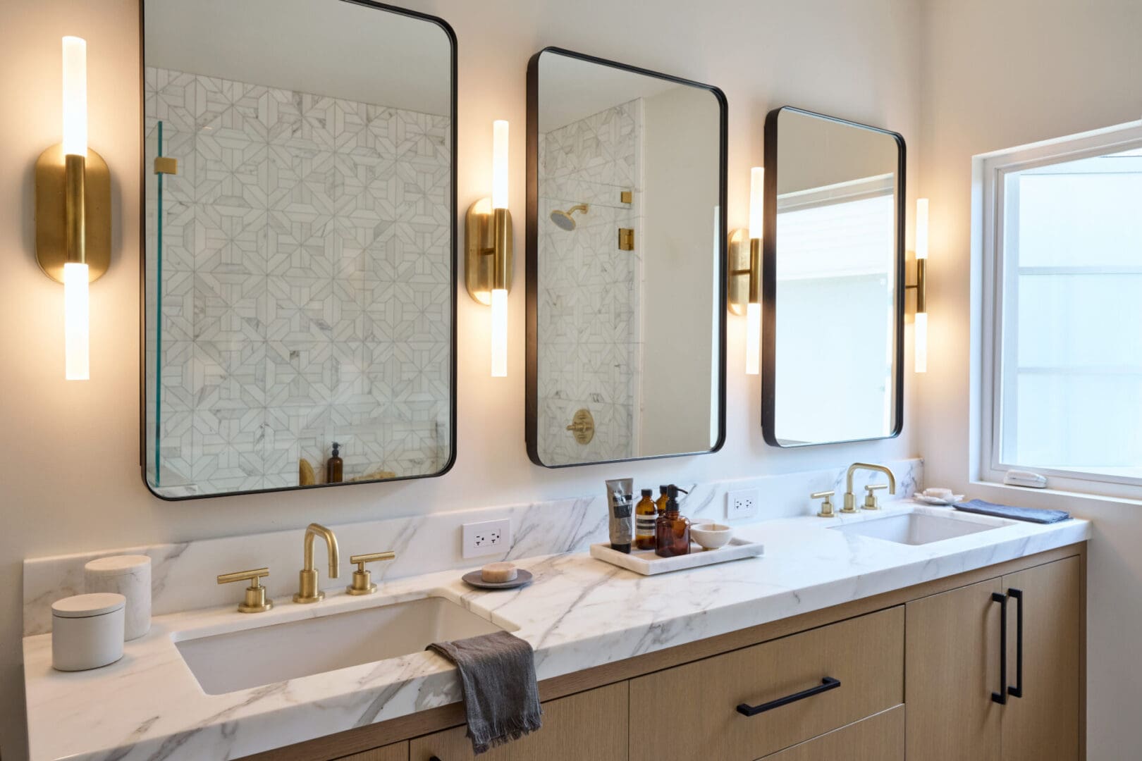 A bathroom with three mirrors and two sinks.